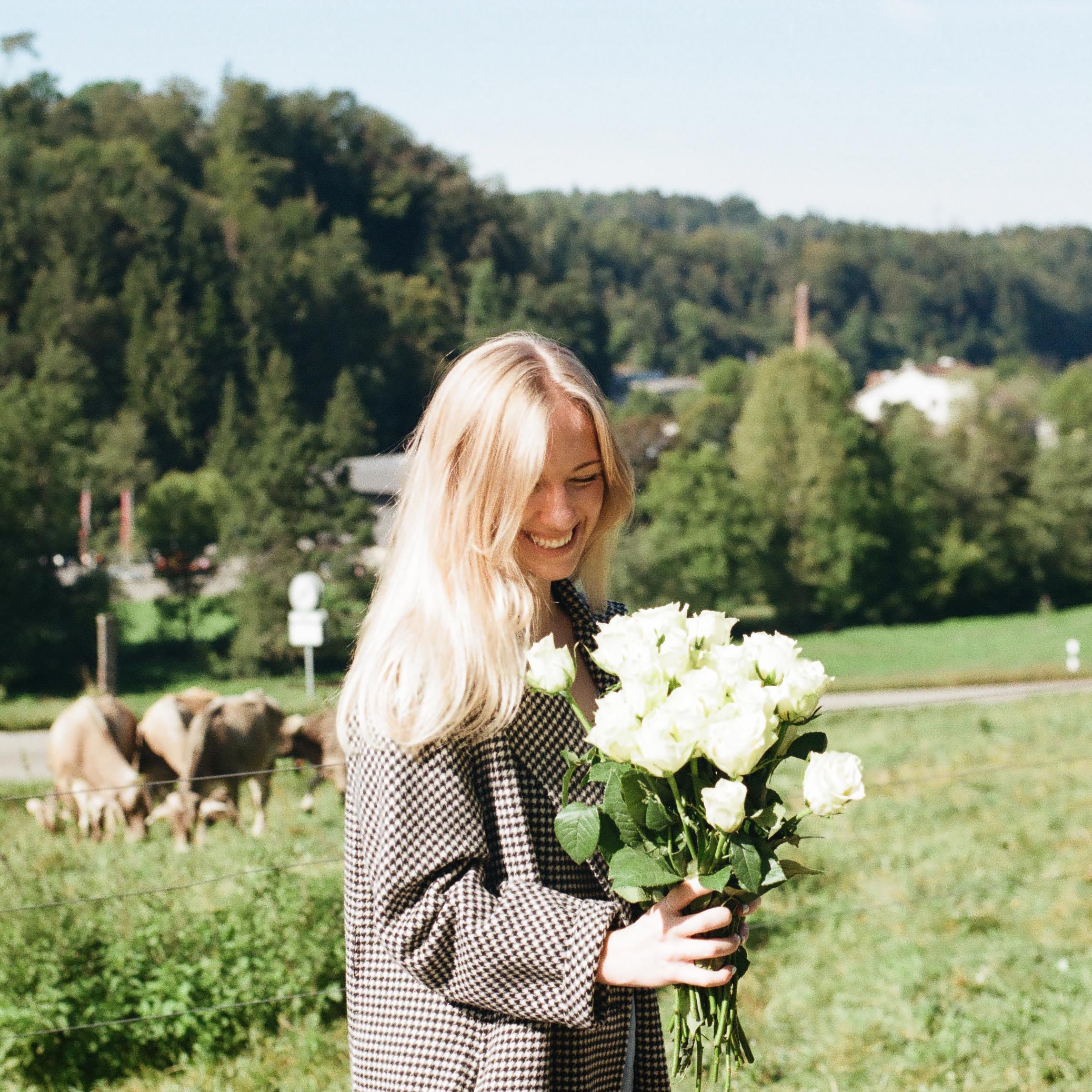 women holding a bouquet of white roses with cows in the background