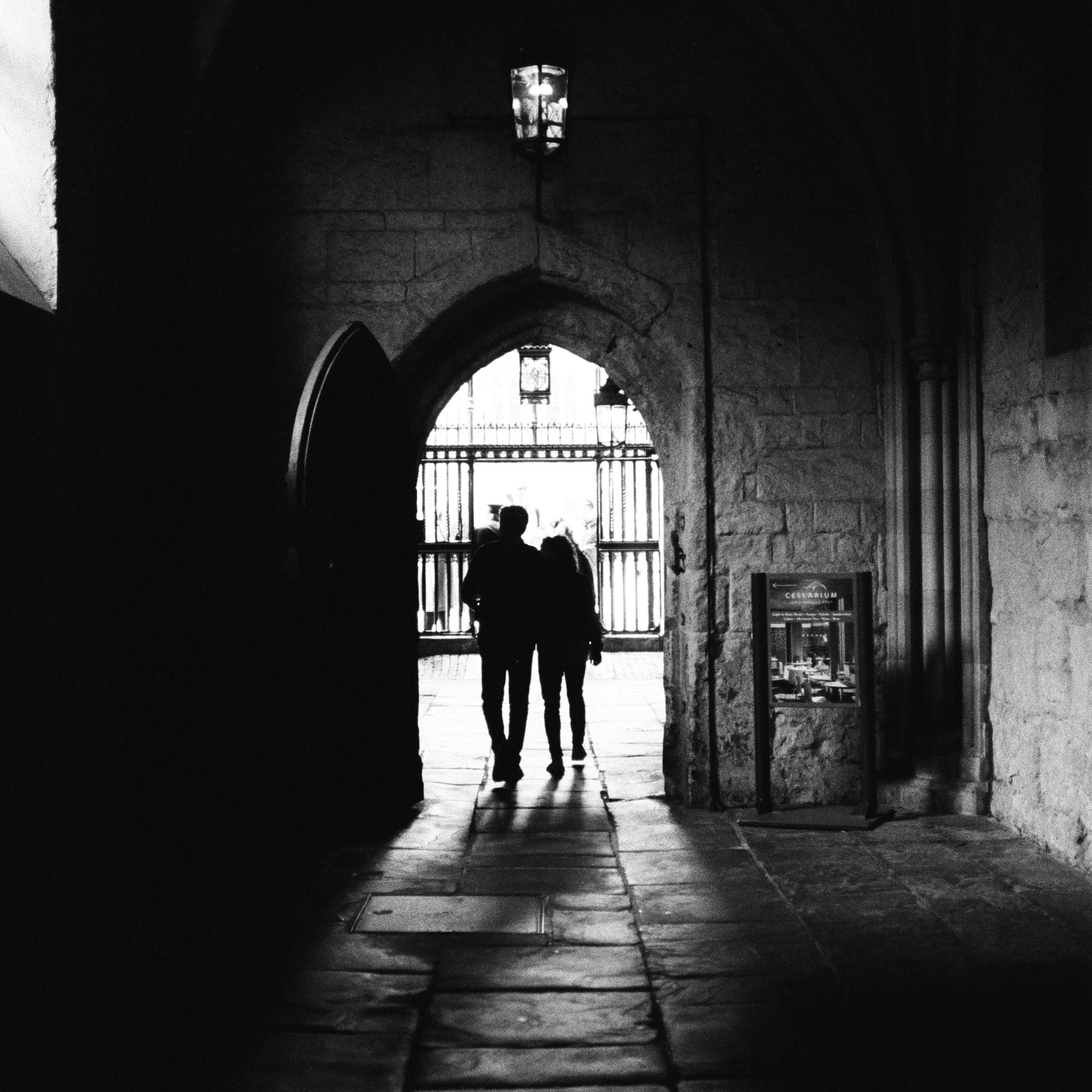 couple walking out of a medieval door towards the light