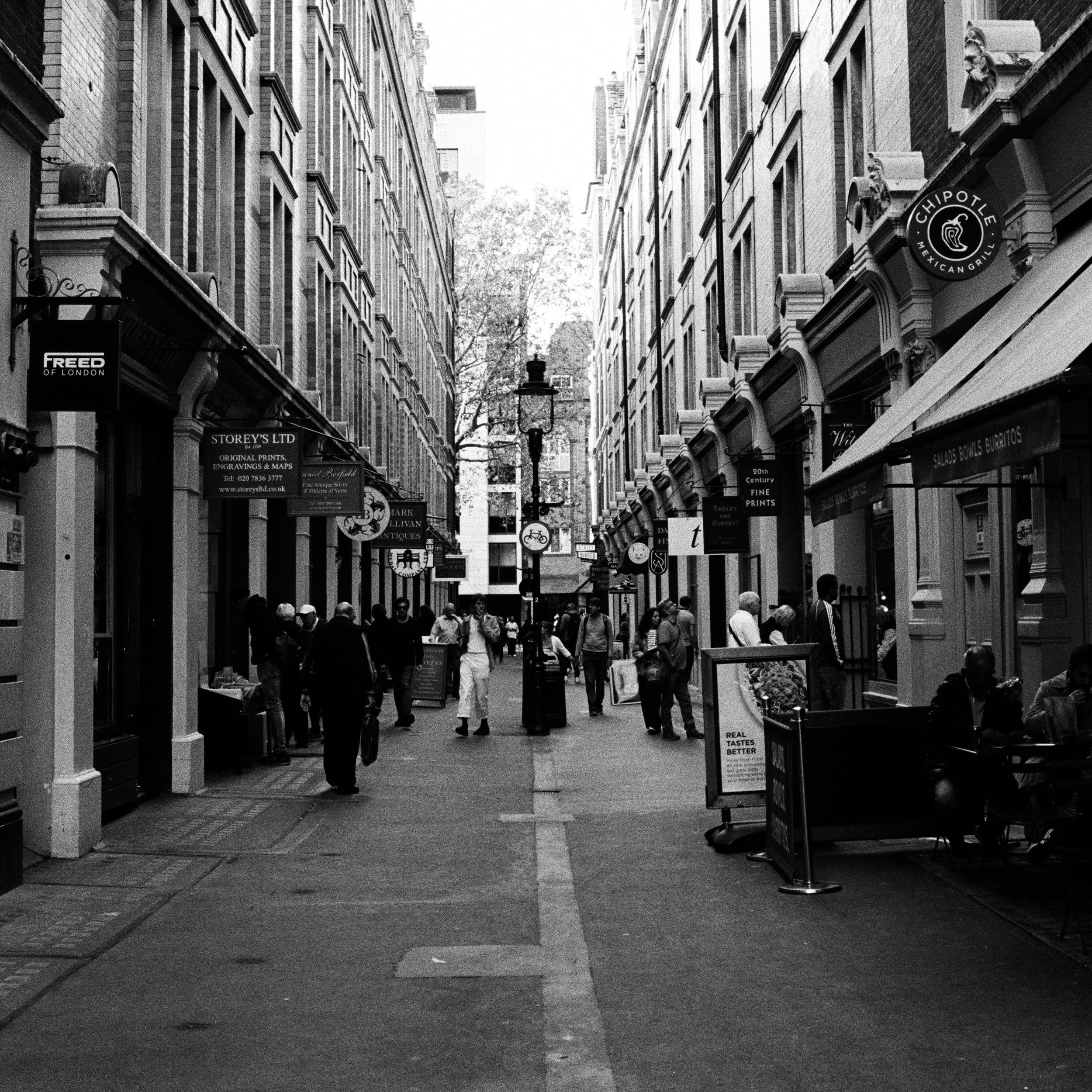 alley with various restaurants and people walking through