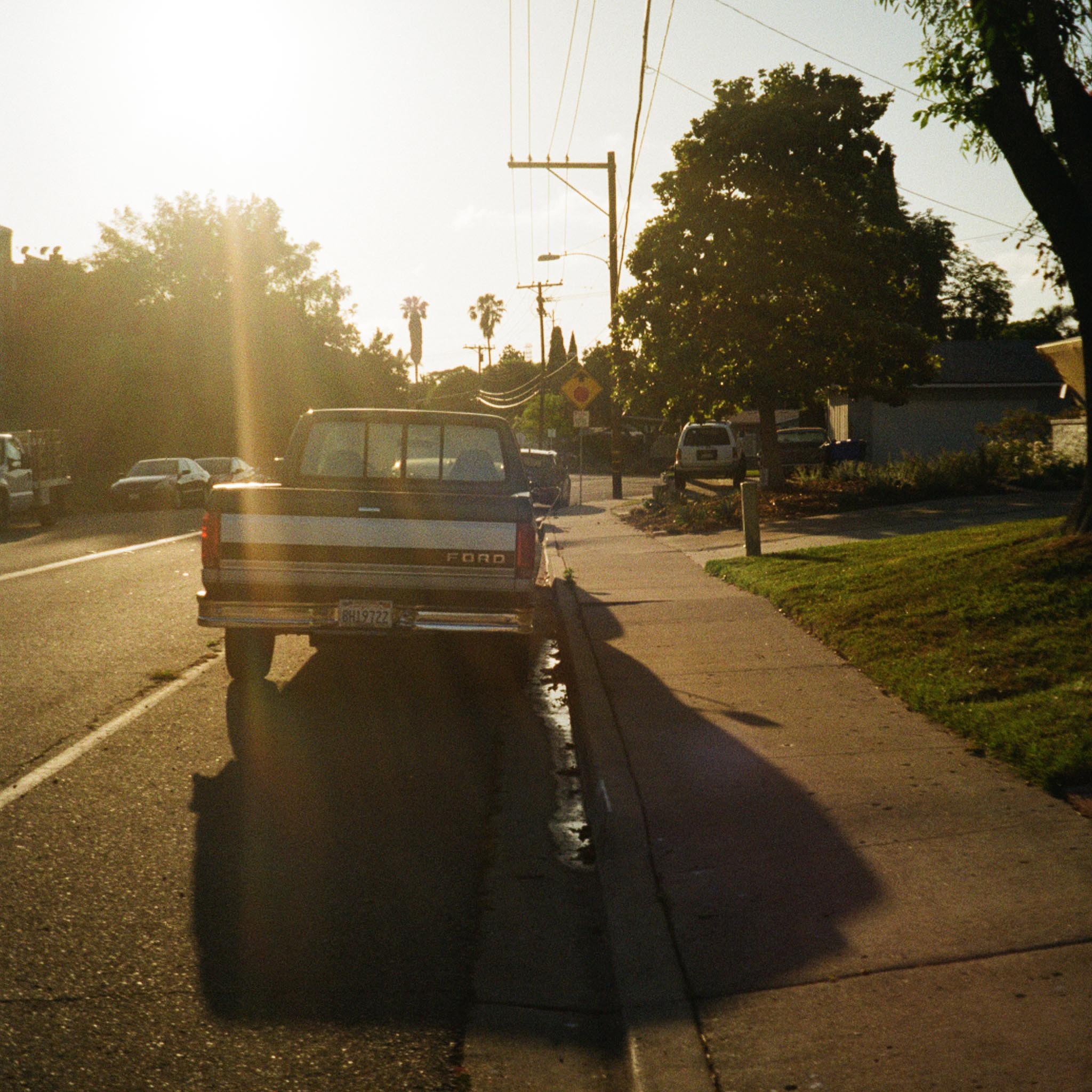 pick-up truck from behind, parked on the side of the road with the sun shining over it