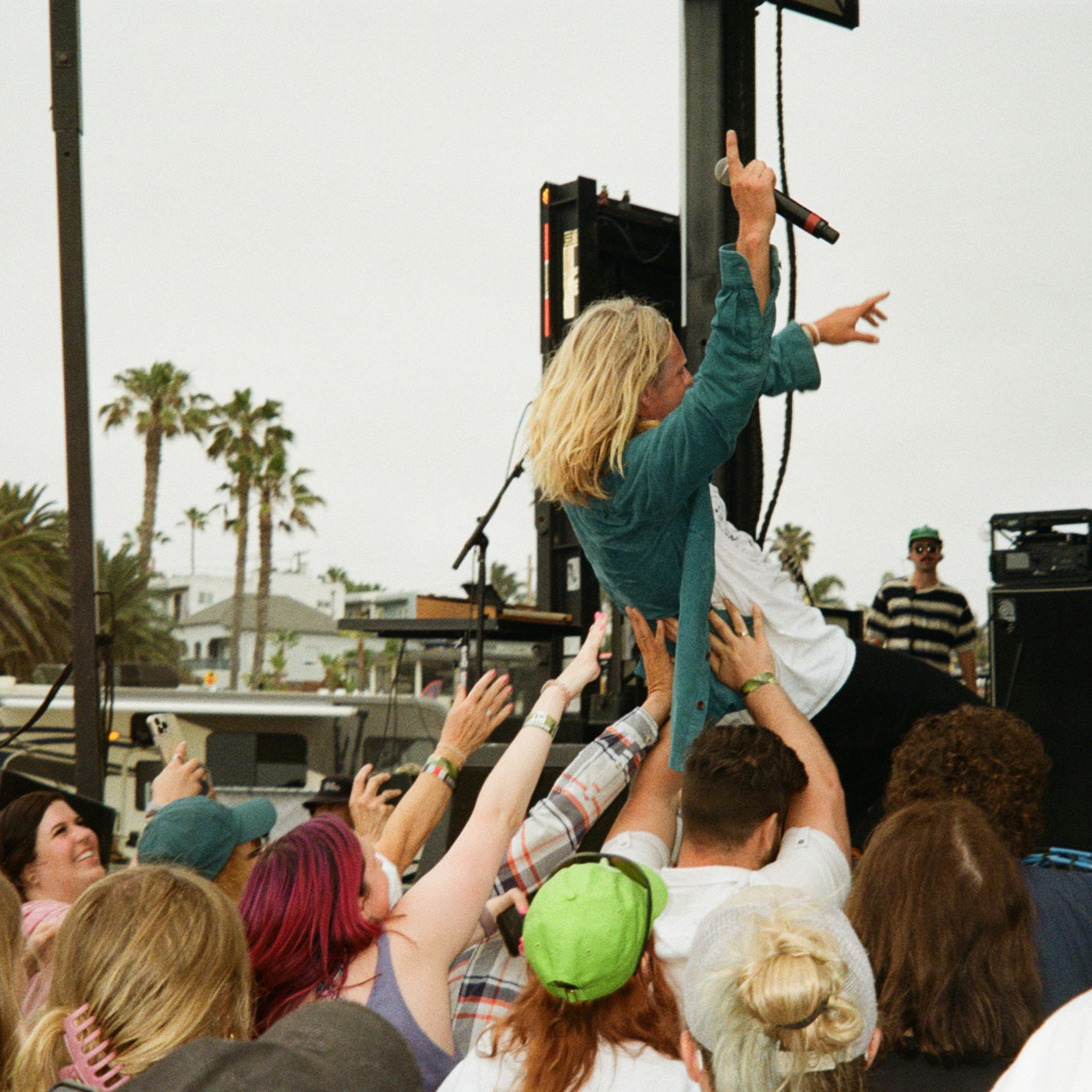 lead singer from the band Switchfoot leaning back into the crowd during a concert