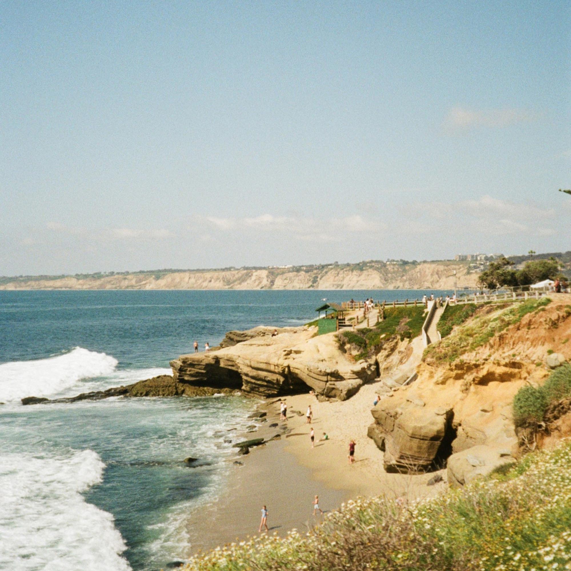 cliffs on the coast with the sea and people walking at the beach below