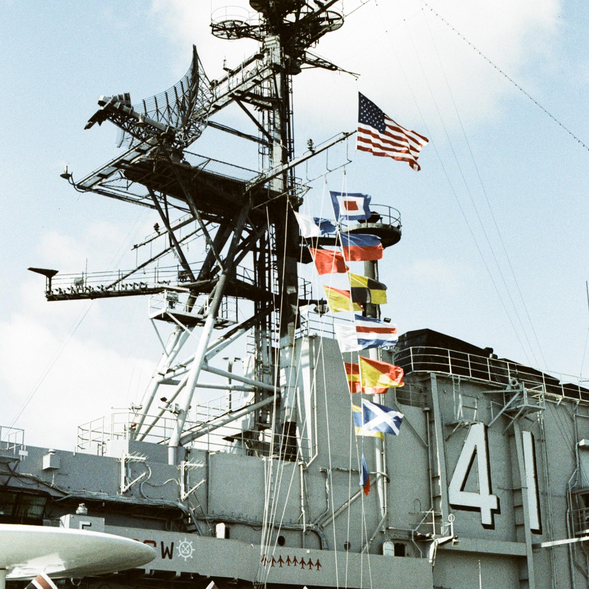 top antenna of an aircraft carrier with various flags on it