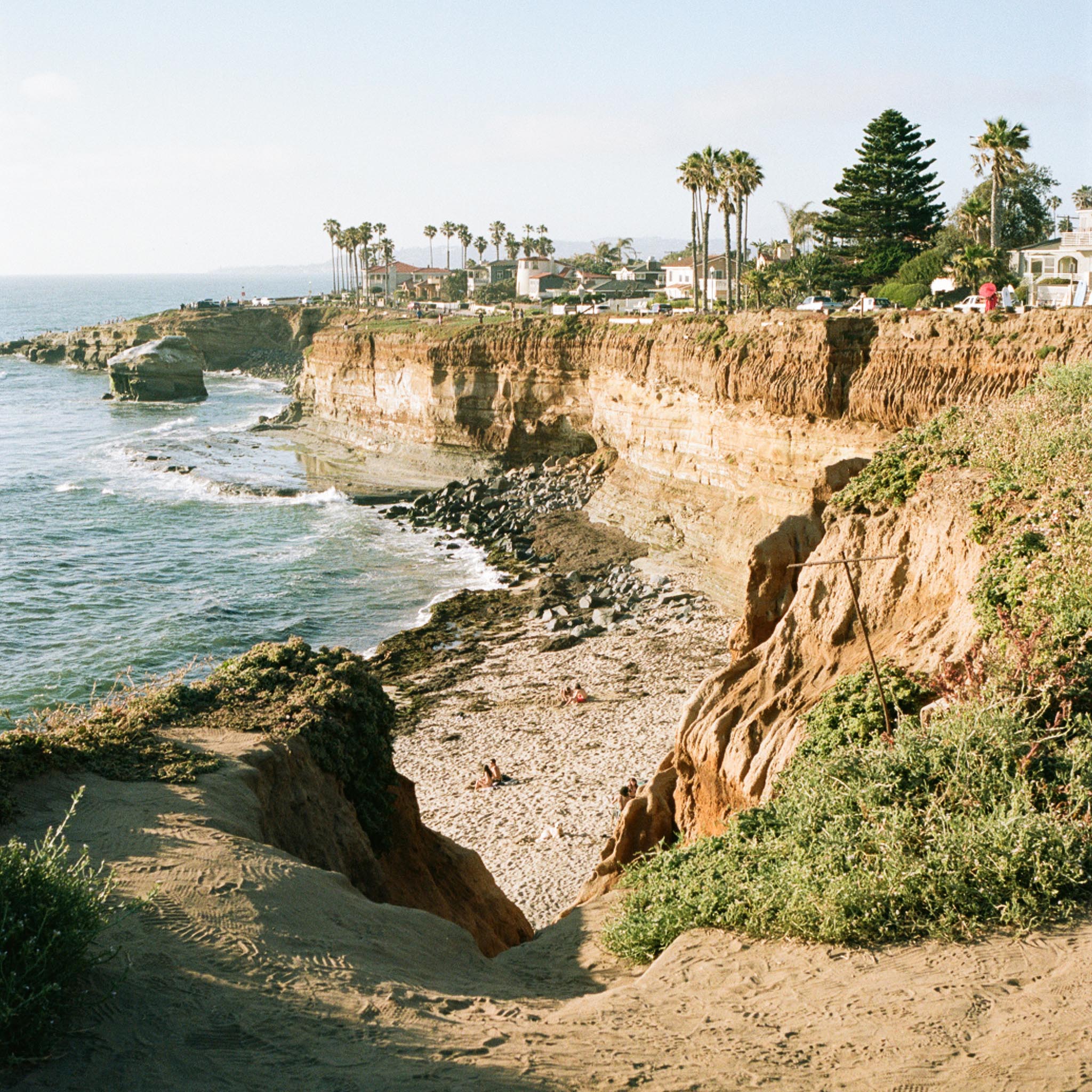 cliffs on the coast with the sea below and palm trees on the shore