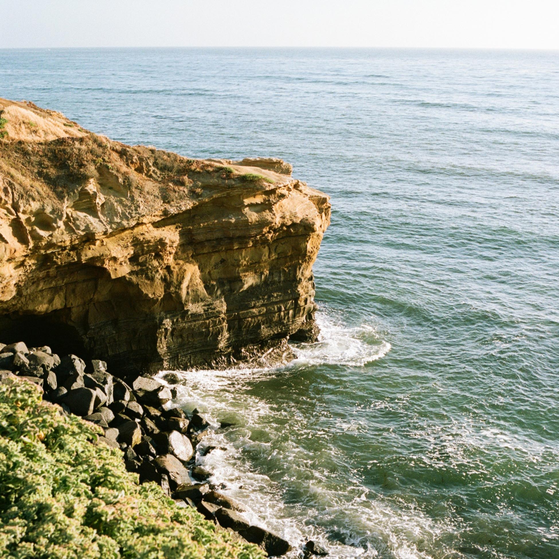 cliff on the seashore with small waves visible in the sea