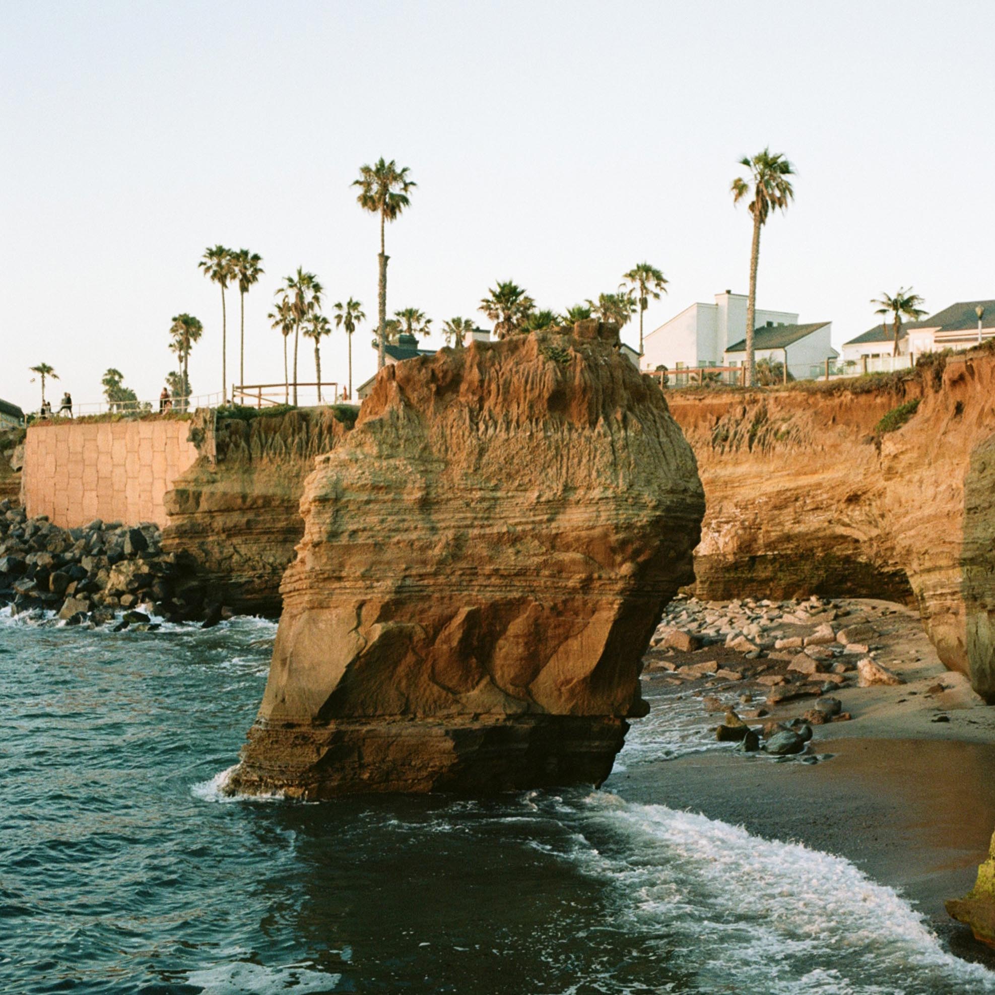lone boulder in the sea next to the shore cliffs