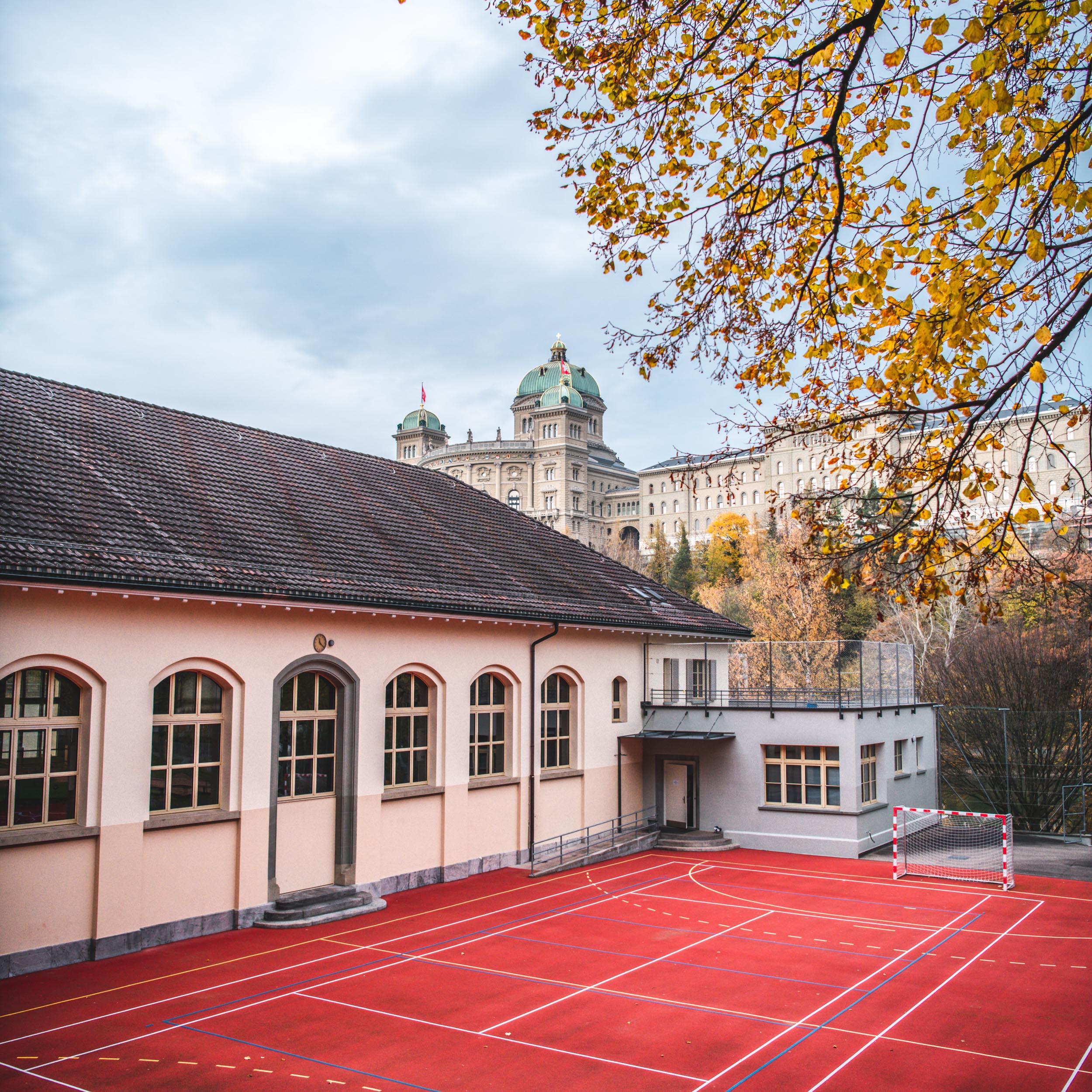 building with sports field next to it and Swiss government building in the background