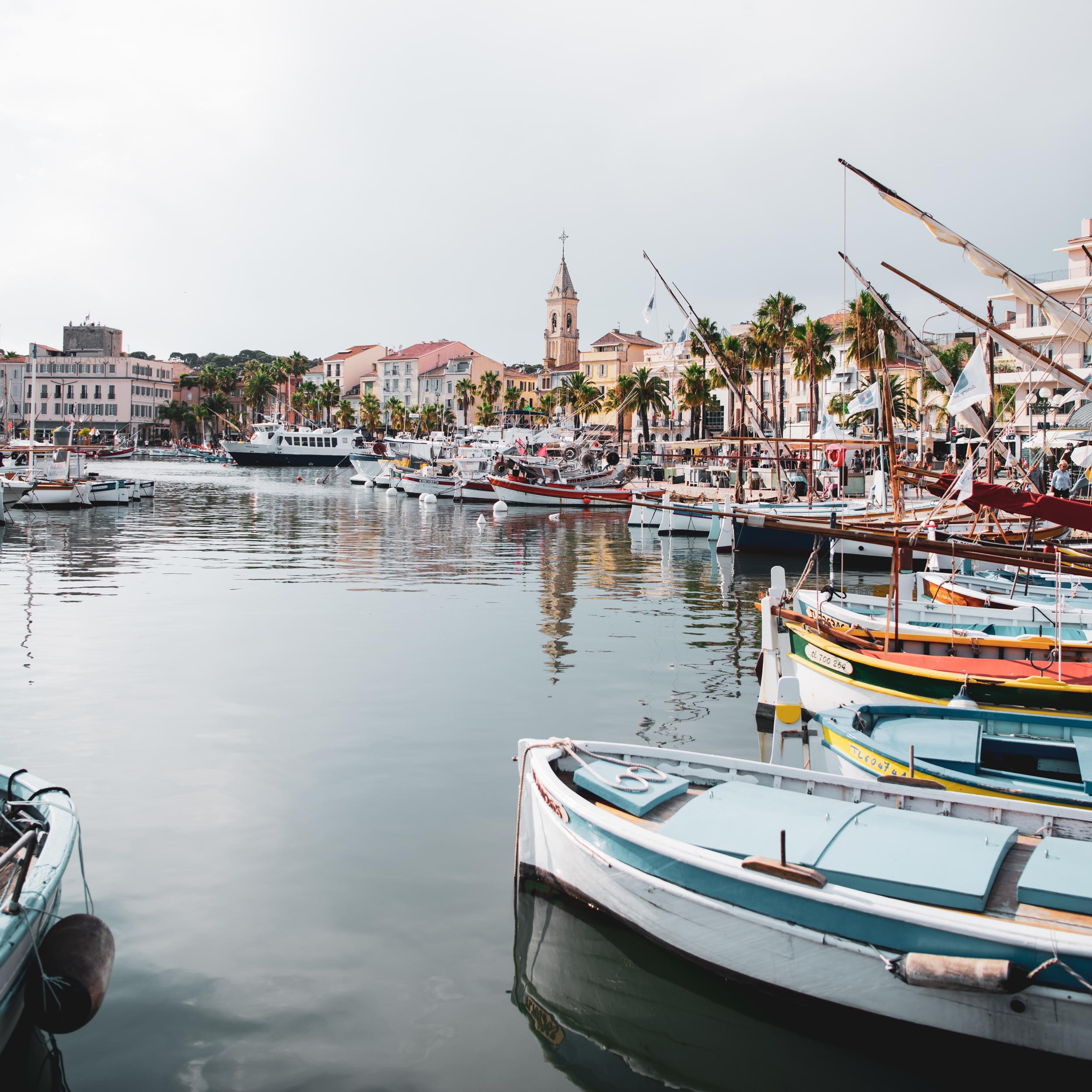 mediterranean harbor with small fishing boats and town next to it