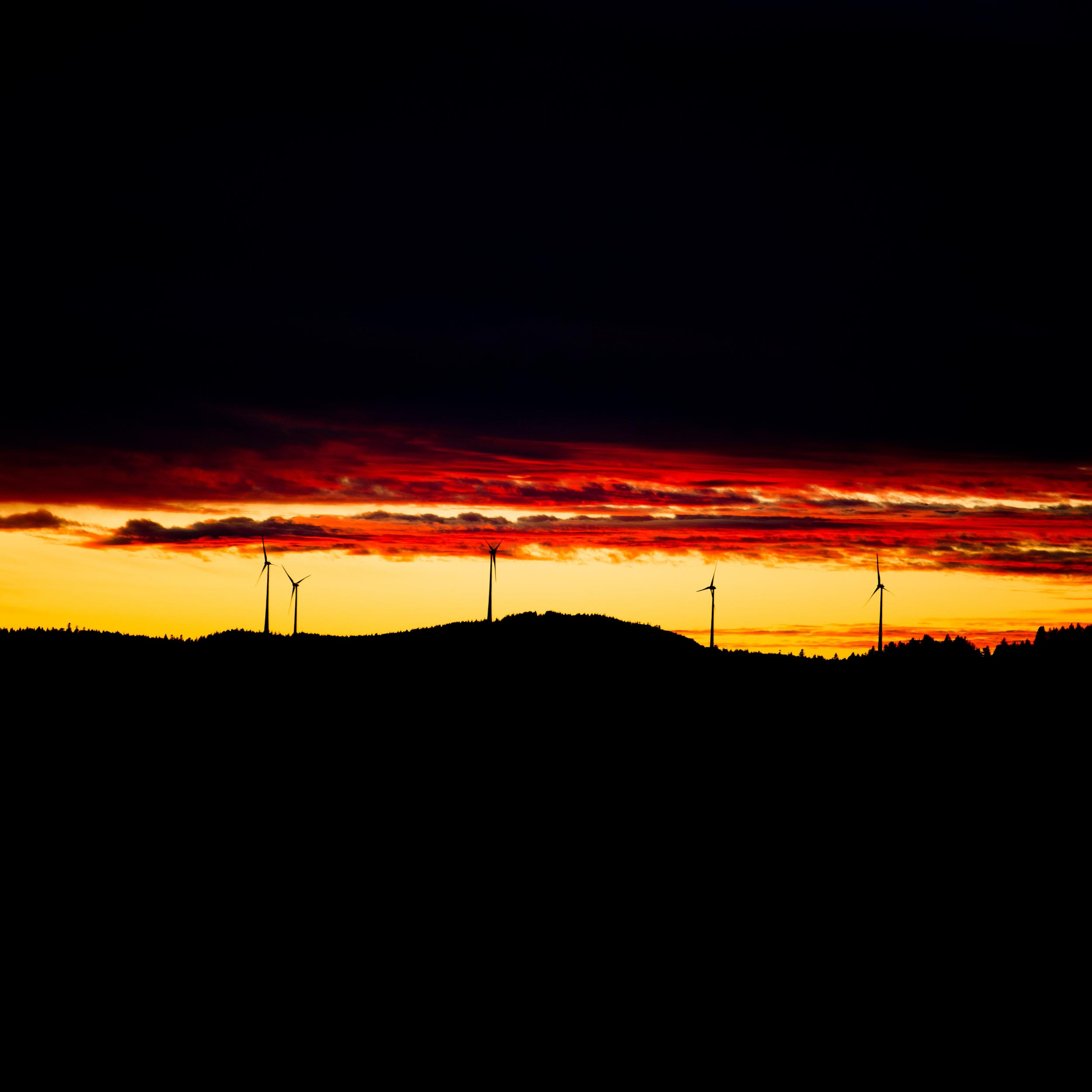 hills with wind turbines and a colorful sunset in the sky