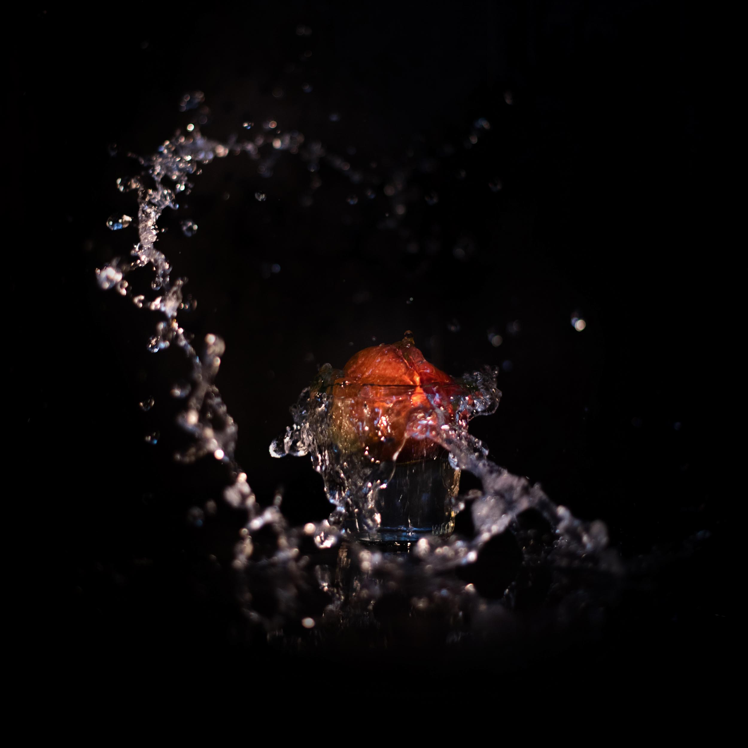red apple in a glass that splashes the water upwards